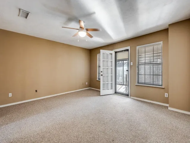 an empty room with chandelier fan and windows