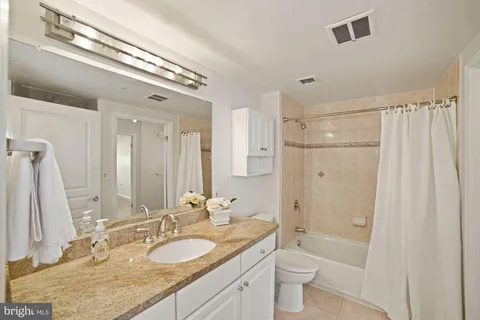 a bathroom with a granite countertop double vanity sink a mirror and a shower