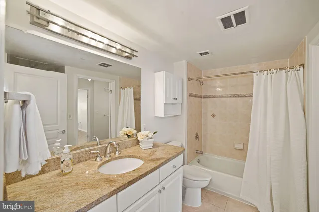 a bathroom with a granite countertop double vanity sink a mirror and a shower