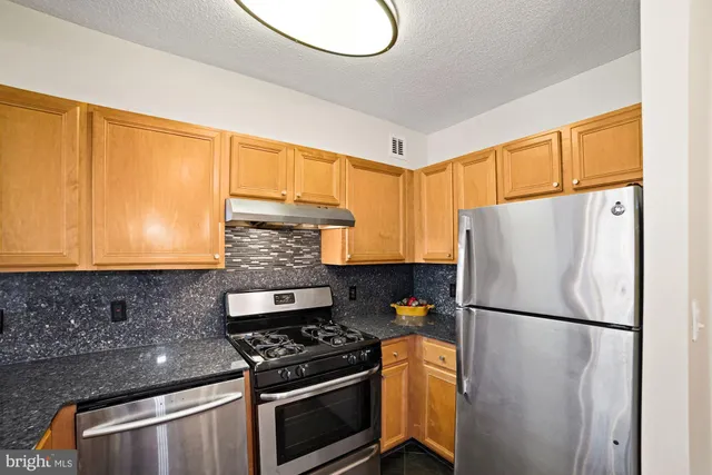 a kitchen with stainless steel appliances granite countertop a refrigerator stove sink and cabinets