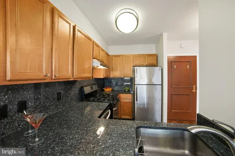 a kitchen with a refrigerator a stove and a sink with wooden floor
