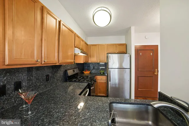 a kitchen with a refrigerator a stove and a sink with wooden floor