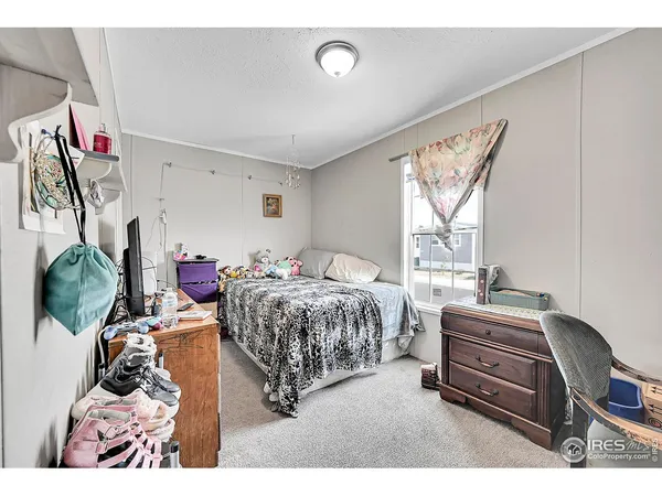a bedroom with a bed next to a window with on the dresser