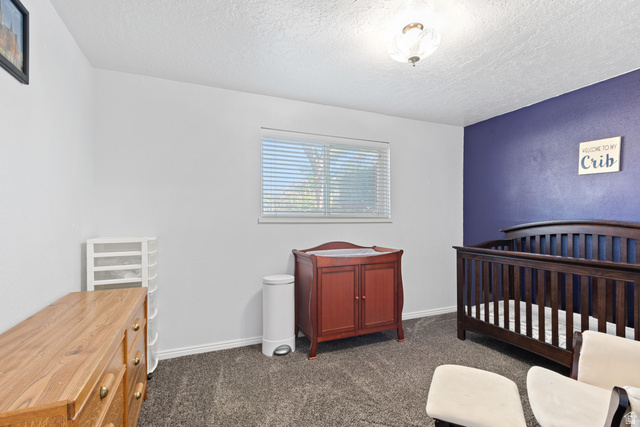 553 North 200 West Bountiful, UT 84010 - Photo 16 of 26 Bedroom featuring a crib, dark carpet, and a textured ceiling