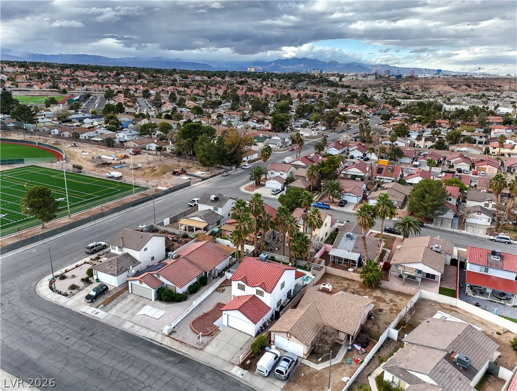 581 Carleton Drive Henderson, NV 89014 - Photo 29 of 37 An aerial perspective reveals a vibrant neighborhood with homes, a sports field, and distant mountains.