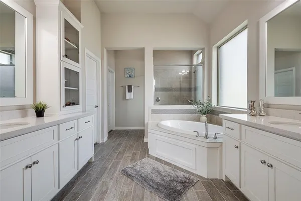 a spacious bathroom with a double vanity sink a mirror and a bathtub