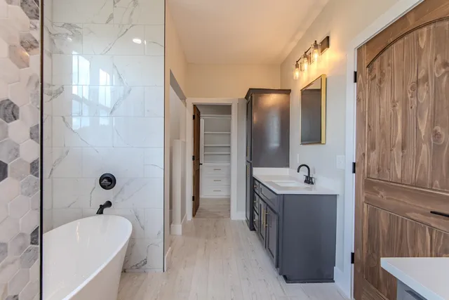a bathroom with a tub sink shower and mirror