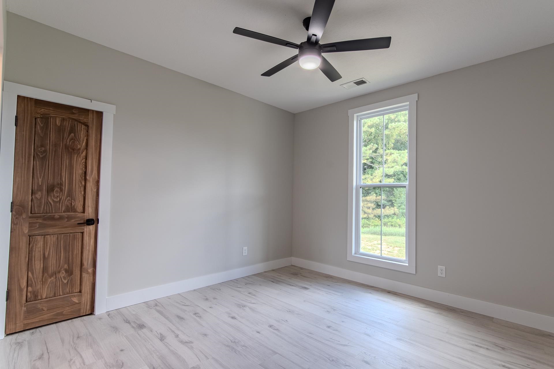 90 Columbus Lane Adamsville, TN 38310 - Photo 26 of 40 an empty room with wooden floor fan and windows