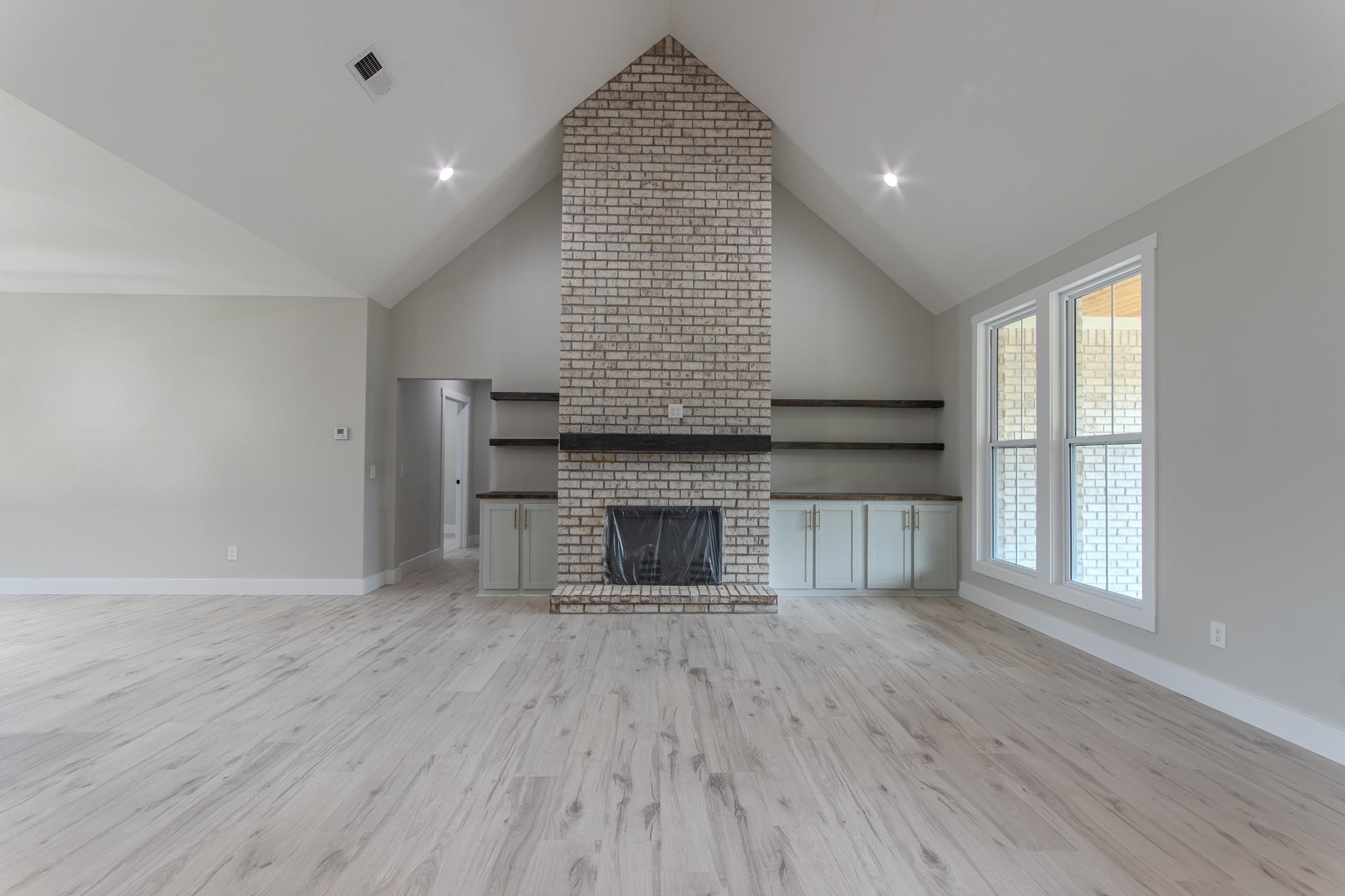 90 Columbus Lane Adamsville, TN 38310 - Photo 8 of 40 an empty room with wooden floor fireplace and windows