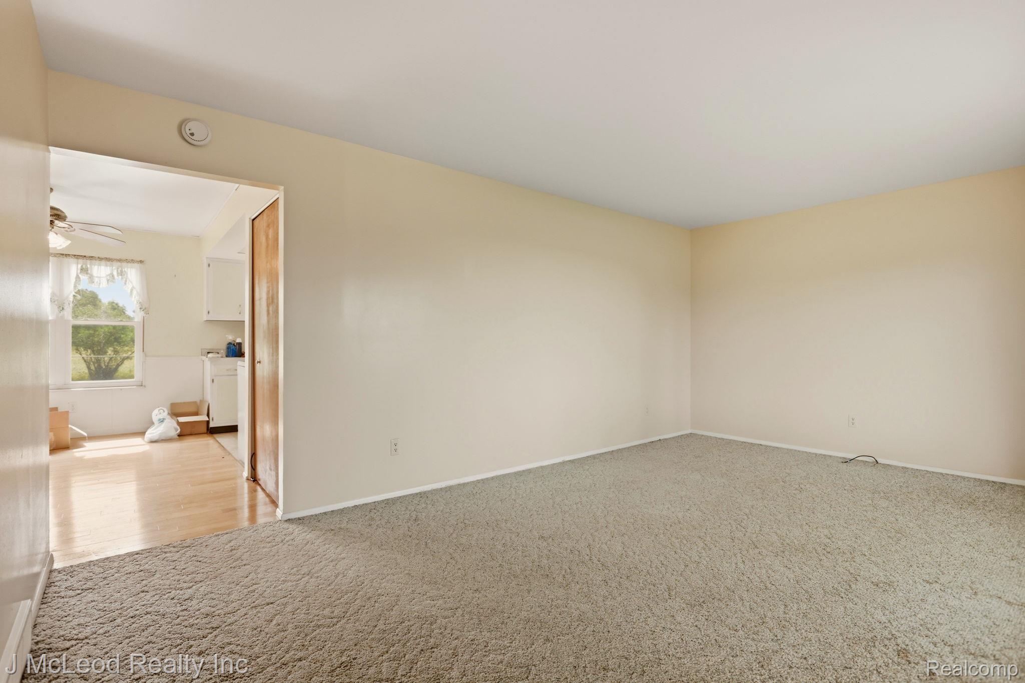 9481 Swaffer Road Vassar, MI 48768 - Photo 10 of 39 Neutral tone wall paint, light-colored carpeting, wood-finish flooring, white ceiling fan