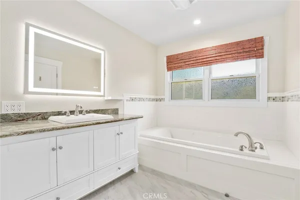 a bathroom with a granite countertop sink mirror and bathtub
