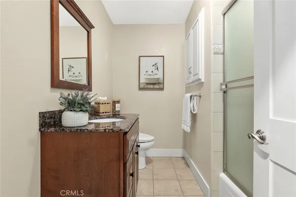 a bath room with a granite countertop sink a toilet and a mirror