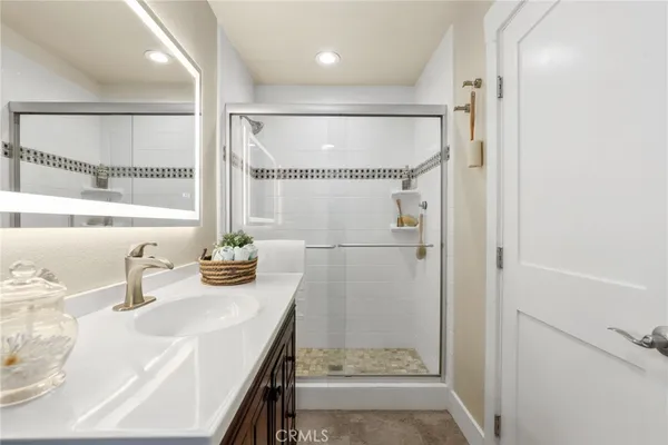 a bathroom with a granite countertop shower sink vanity and mirror