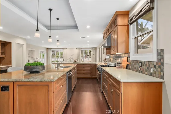a large kitchen with stainless steel appliances granite countertop a sink a stove and a wooden floors