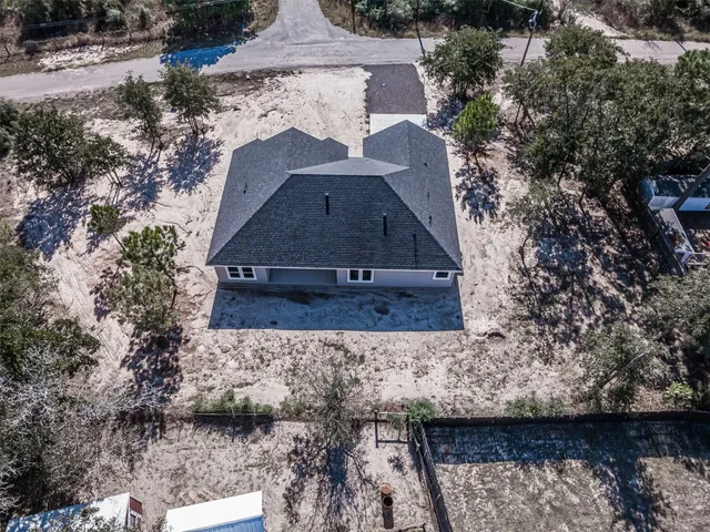 an aerial view of house with yard and trees in the background