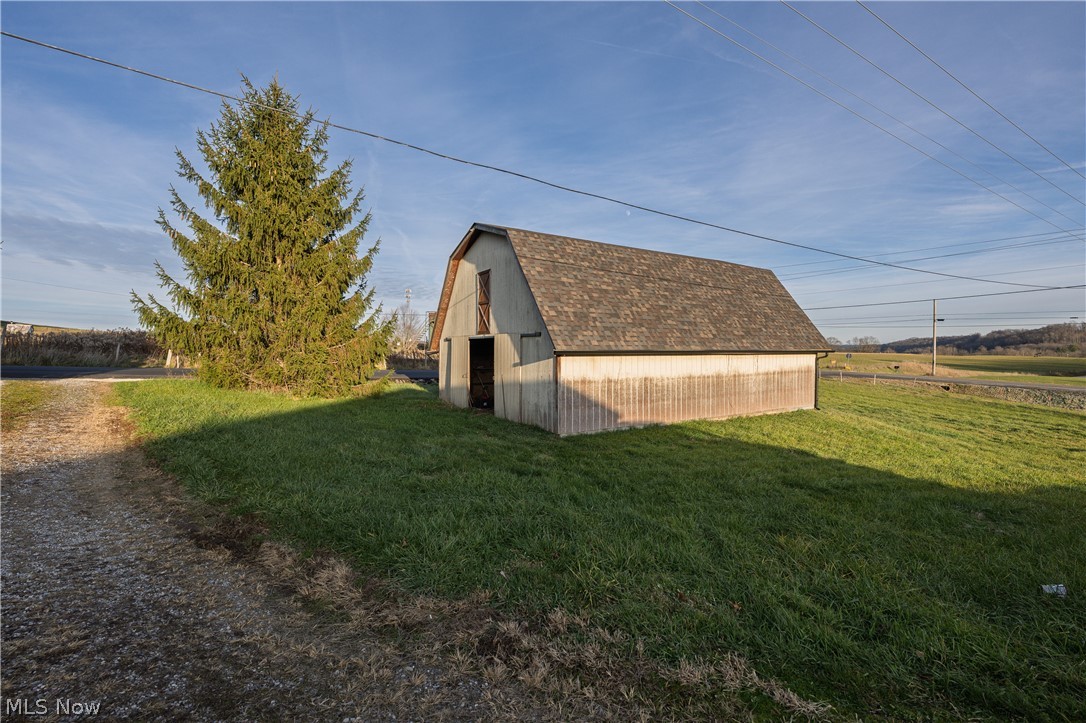 8200 Cutler Road Southwest Sherrodsville, OH 44675 - Photo 5 of 26 View of property exterior featuring a gambrel roof, a barn, an outbuilding, a yard, and a shingled roof