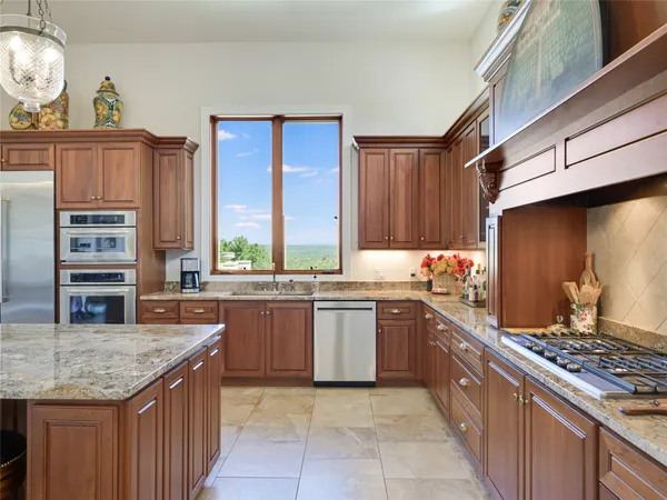 a kitchen with kitchen island granite countertop a sink stove and cabinets