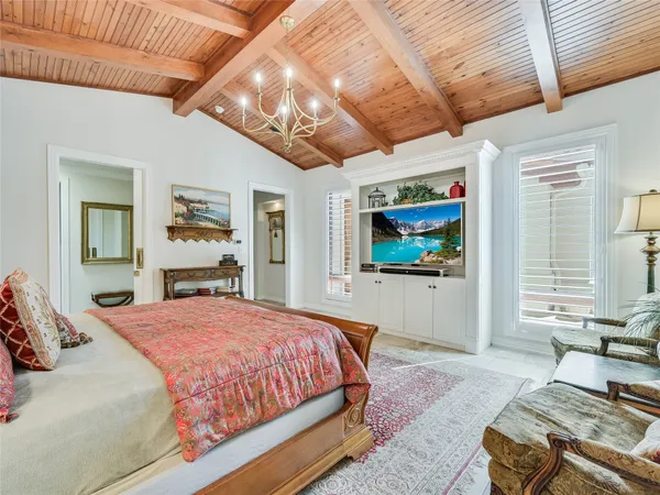a bedroom with a large bed a flat tv screen and next to a window