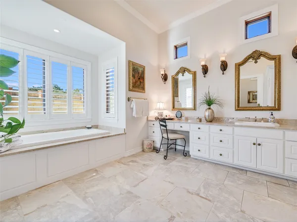 a large bathroom with double vanity sinks a large mirror and a bathtub next to a window