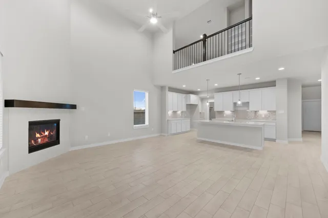 a view of an empty room and kitchen with fireplace