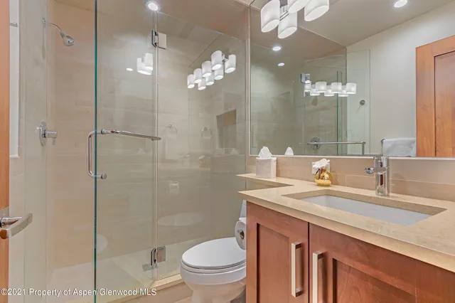 a bathroom with a sink a toilet a mirror and shower