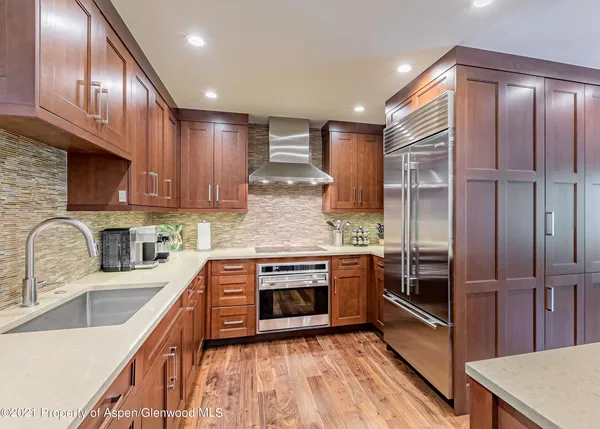 a kitchen with stainless steel appliances granite countertop a sink stove refrigerator and cabinets