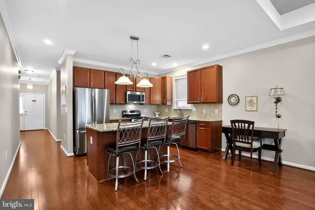 a kitchen with stainless steel appliances a dining table chairs stove and wooden floor