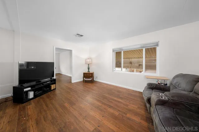 a living room with furniture and a flat screen tv with wooden floor