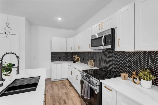 a kitchen with a sink stove and white cabinets