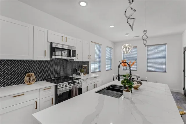a kitchen with stainless steel appliances granite countertop a stove a sink dishwasher and microwave with wooden floor