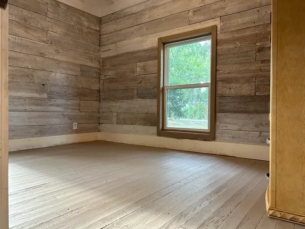 an empty room with wooden floor cabinet and windows