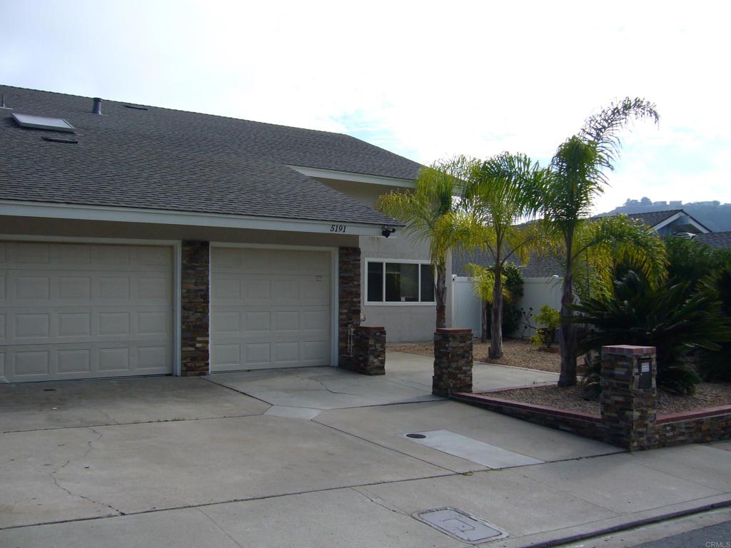 a backyard of a house with potted plants and palm trees