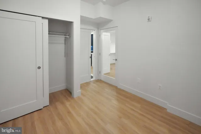 a view of an empty room with wooden floor and closet