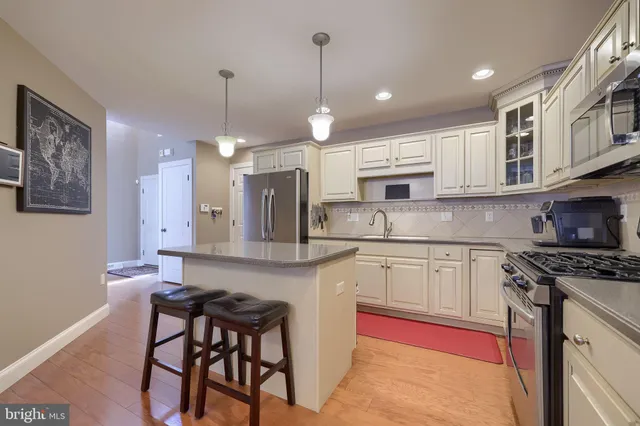 a kitchen with stainless steel appliances granite countertop a stove a sink a microwave a refrigerator and cabinets