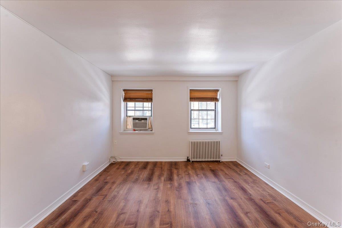 78-11 Main Street, Unit 1G Queens, NY 11367 - Photo 1 of 15 an empty room with wooden floor and windows