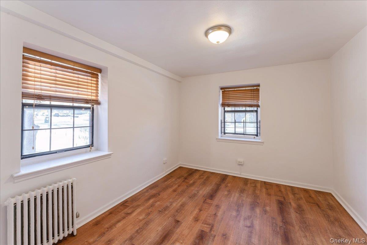78-11 Main Street, Unit 1G Queens, NY 11367 - Photo 6 of 15 an empty room with a window and wooden floor