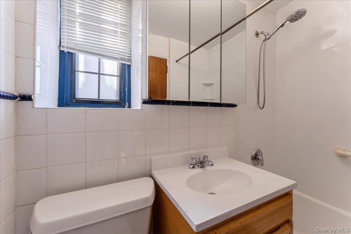 78-11 Main Street, Unit 1G Queens, NY 11367 - Photo 9 of 15 a bathroom with a sink a toilet and a window