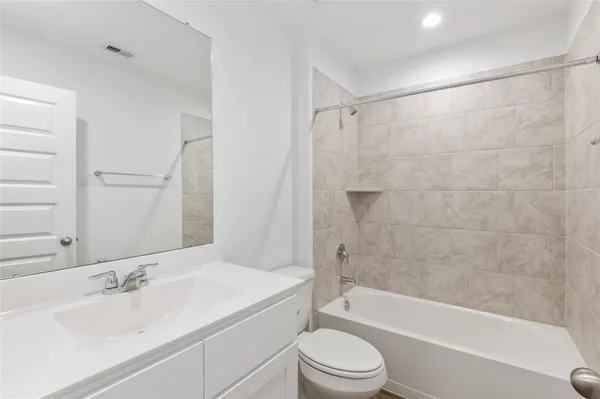 a bathroom with a bathtub shower sink vanity and toilet
