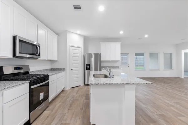 a large kitchen with granite countertop a large counter top stainless steel appliances and cabinets