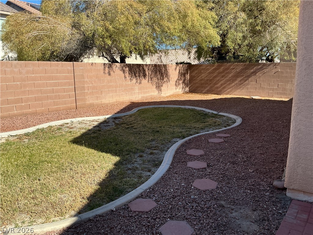 8108 Roundup Ridge Street Las Vegas, NV 89131 - Photo 20 of 21 A low-maintenance backyard retreat featuring a curving patch of natural ground cover amidst decorative gravel and stepping stones.