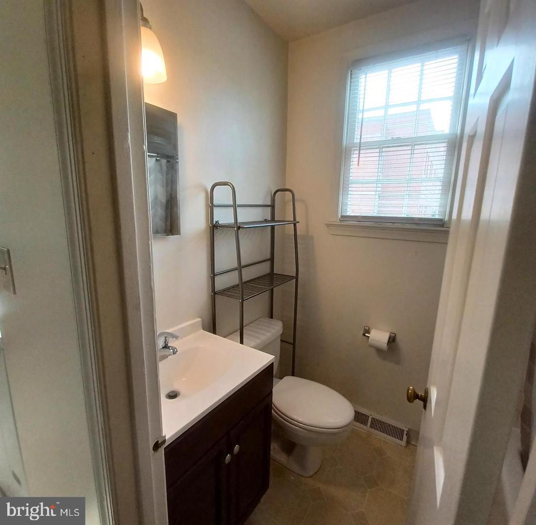 301 North West Street, Unit 1 Alexandria, VA 22314 - Photo 9 of 16 a bathroom with a granite countertop toilet a sink a mirror and a window
