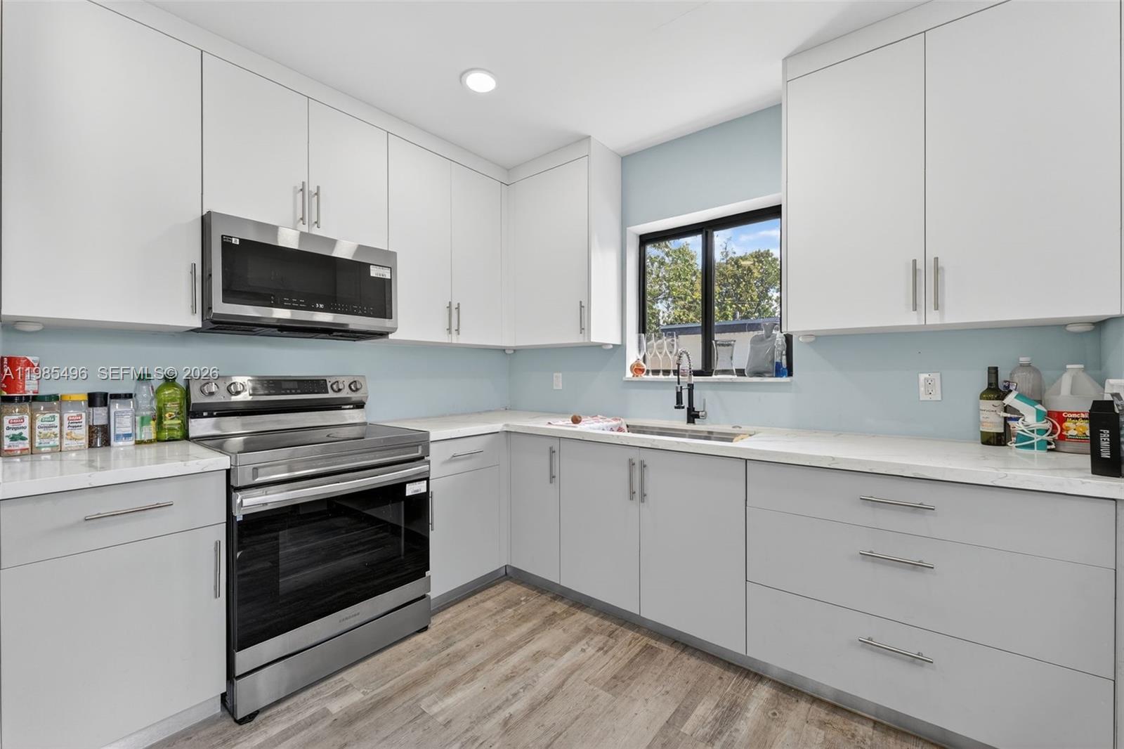 440 East 37th Street Hialeah, FL 33013 - Photo 7 of 27 a kitchen with granite countertop a stove a microwave a sink and cabinets