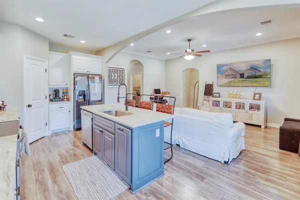 a large kitchen with stainless steel appliances a large counter top a couch and a view of living room