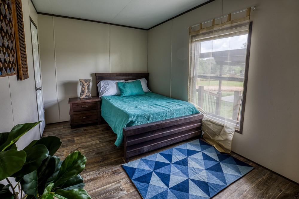 35418 Tompkins Road Hempstead, TX 77445 - Photo 17 of 50 a bedroom with a bed lamp and a potted plant
