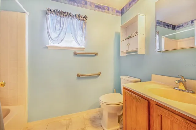 an empty room with a chandelier fan and windows