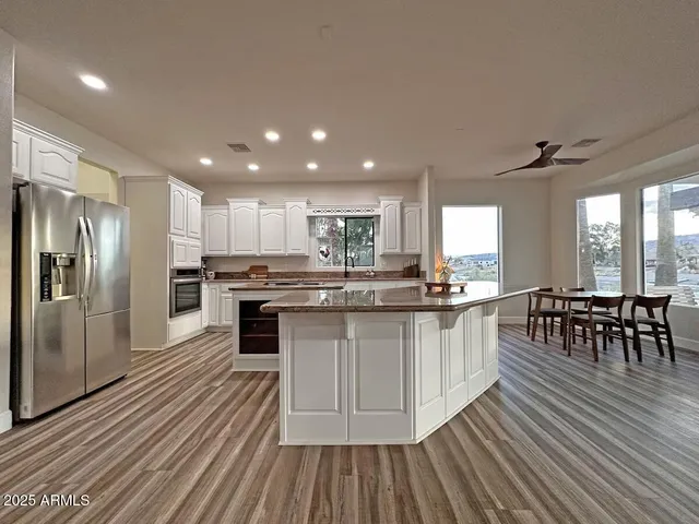 a kitchen with stainless steel appliances granite countertop a stove refrigerator and a dining table with wooden floor