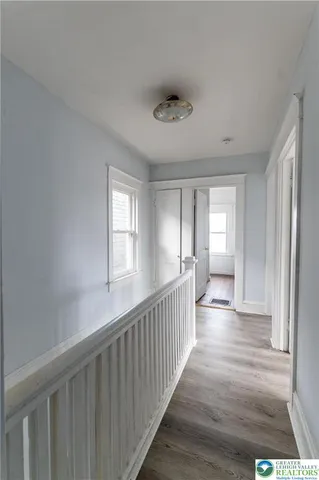 a view of a hallway with wooden floor and windows