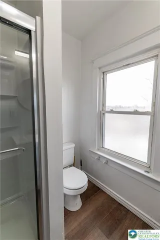 a white toilet sitting next to a window in a bathroom