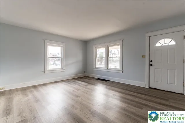 a view of an empty room with wooden floor and a window