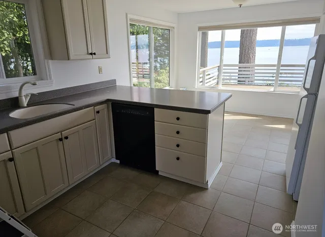 a kitchen with granite countertop a sink a stove top oven and cabinetry